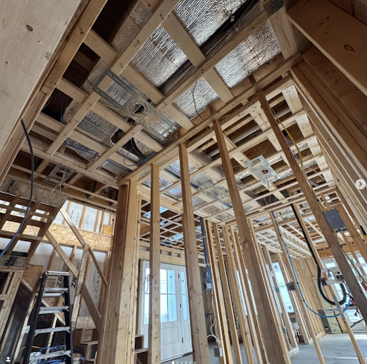 Freshly framed ductwork with insulated ducts routed between floor joists during a Temp Rise installation